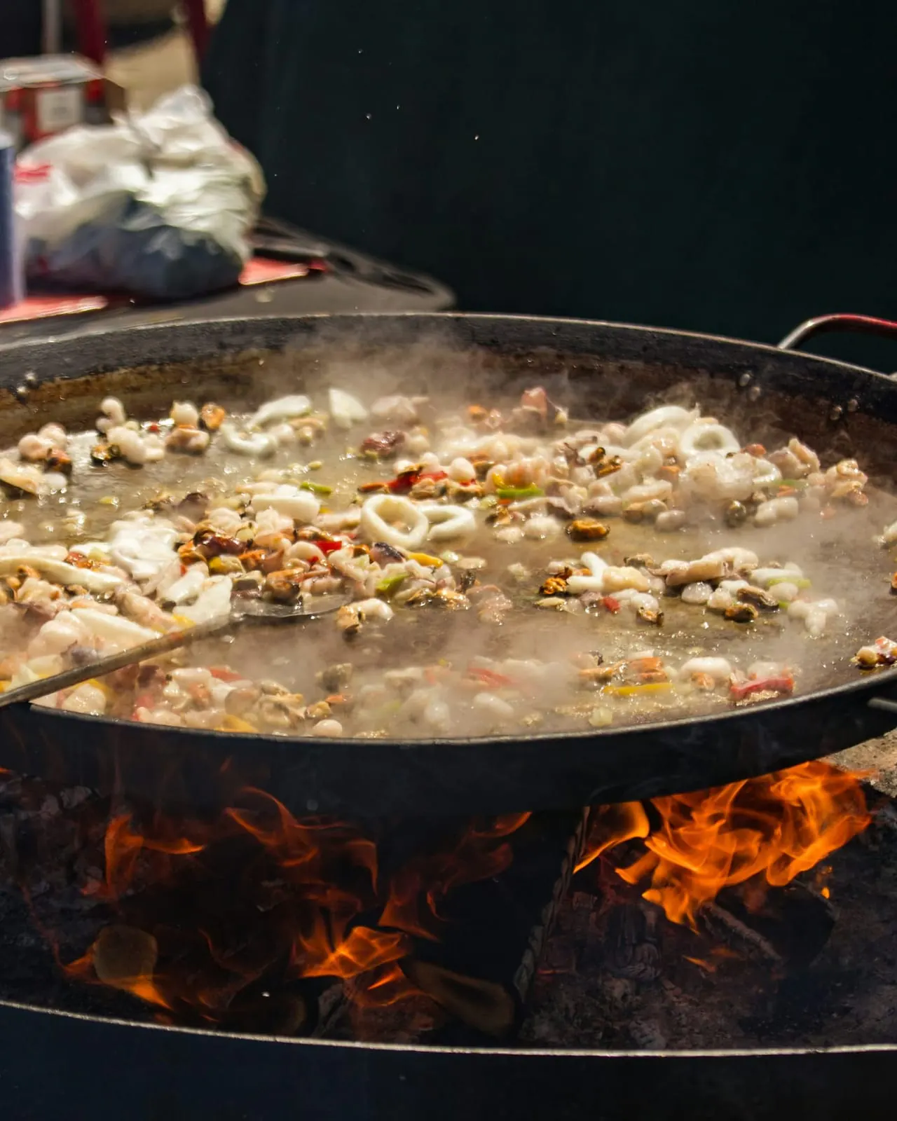 Paella gigante cocinándose a fuego de leña en un festival gastronómico