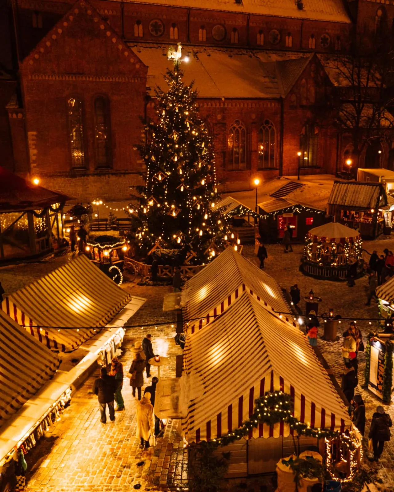 Mercado navideño de noche con puestos de madera iluminados con luces cálidas